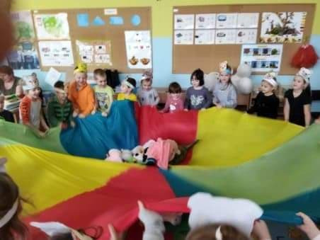 Na zdjęciu znajdują się dzieci z oddziałów przedszkolnych. Dzieci tańczą. Trzymają kolorową chustą animacyjne.