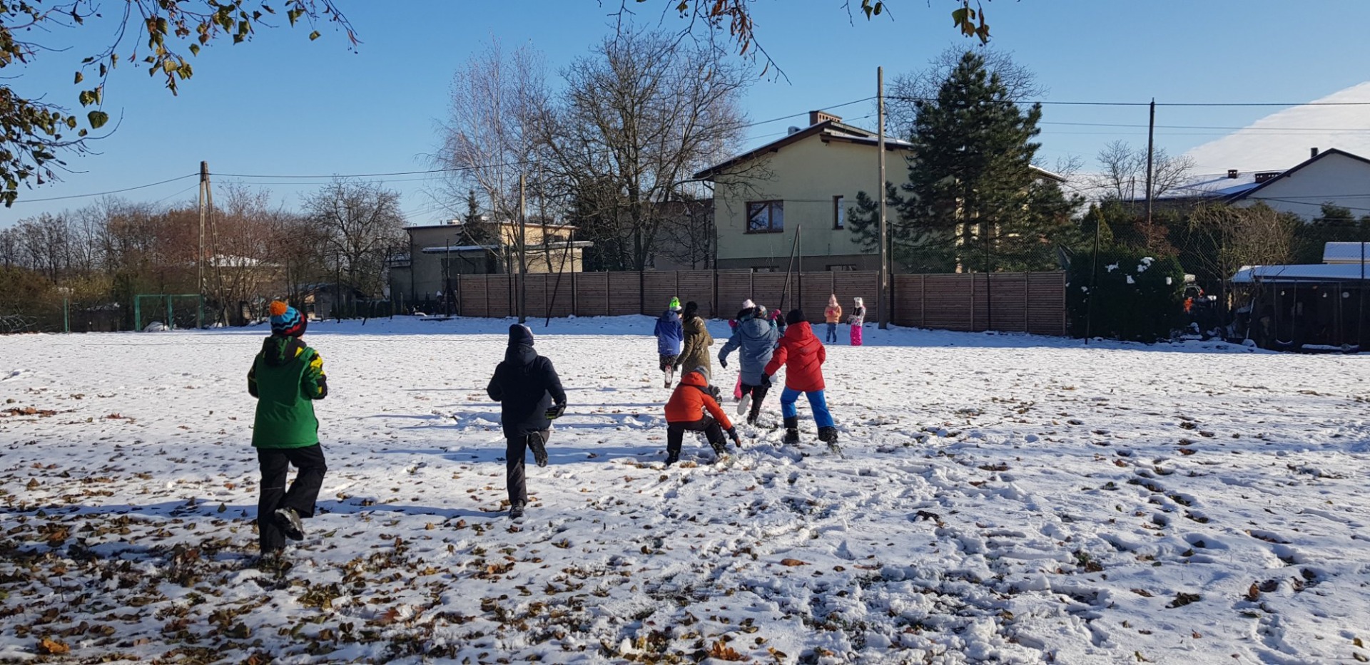 Uczniowie w zimowych ubraniach rzucają się śnieżkami