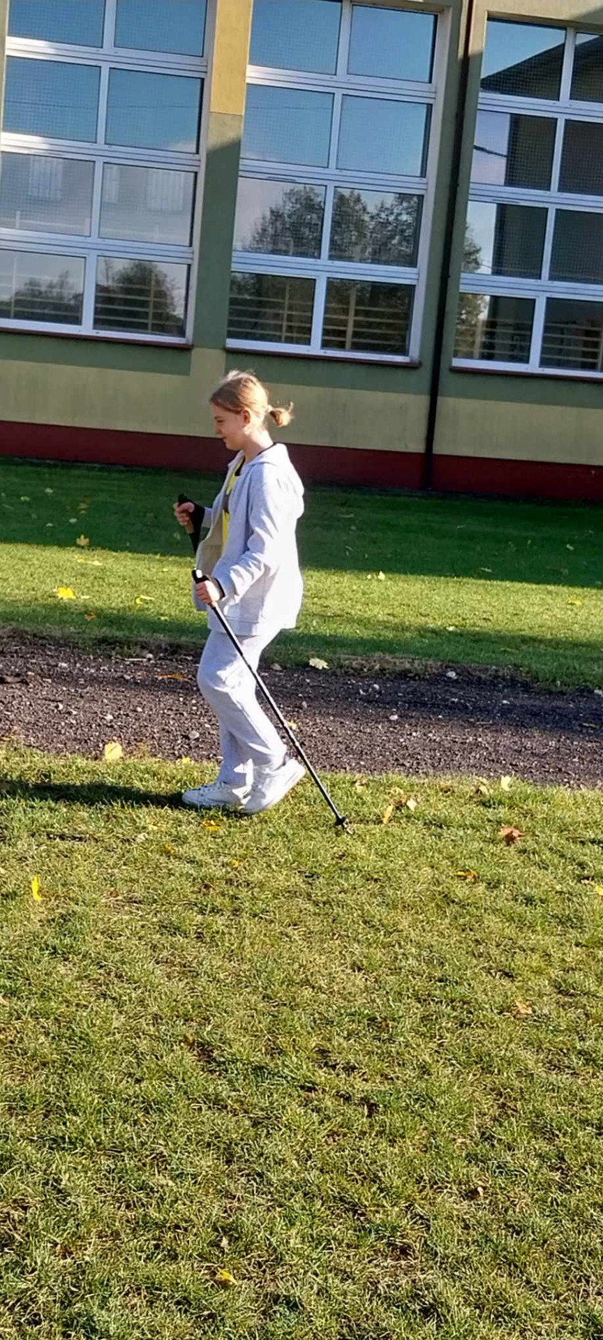 Uczniowie uprawiają nordic walking na szkolnym boisku