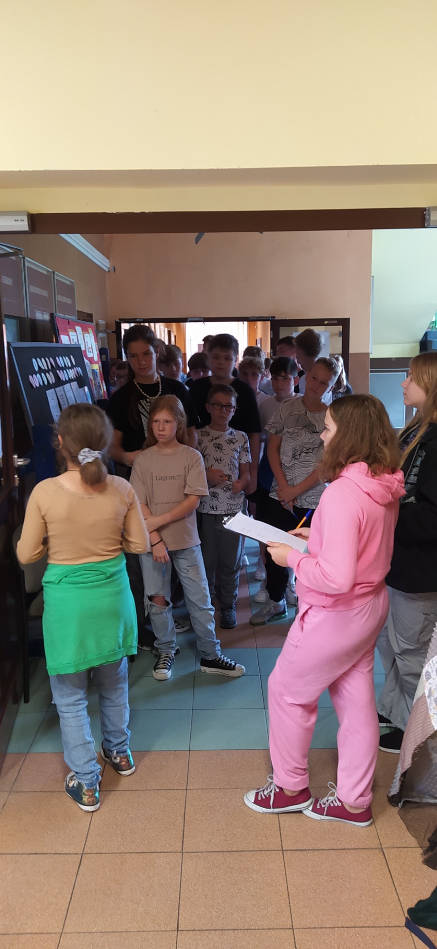 Uczniowie klasy 7 ubrani w kolorowe bluzy słuchają regulaminu wyborczego