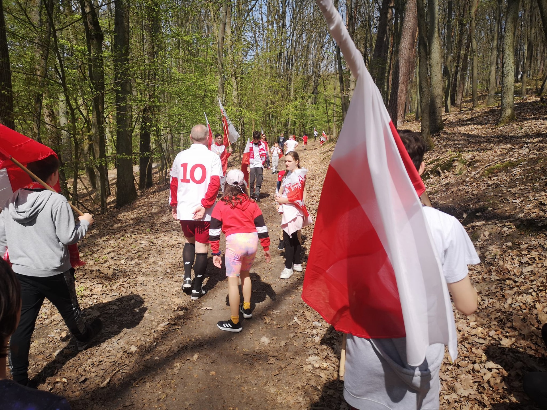 Grupa ludzi w biało-czerwonych strojach w lesie