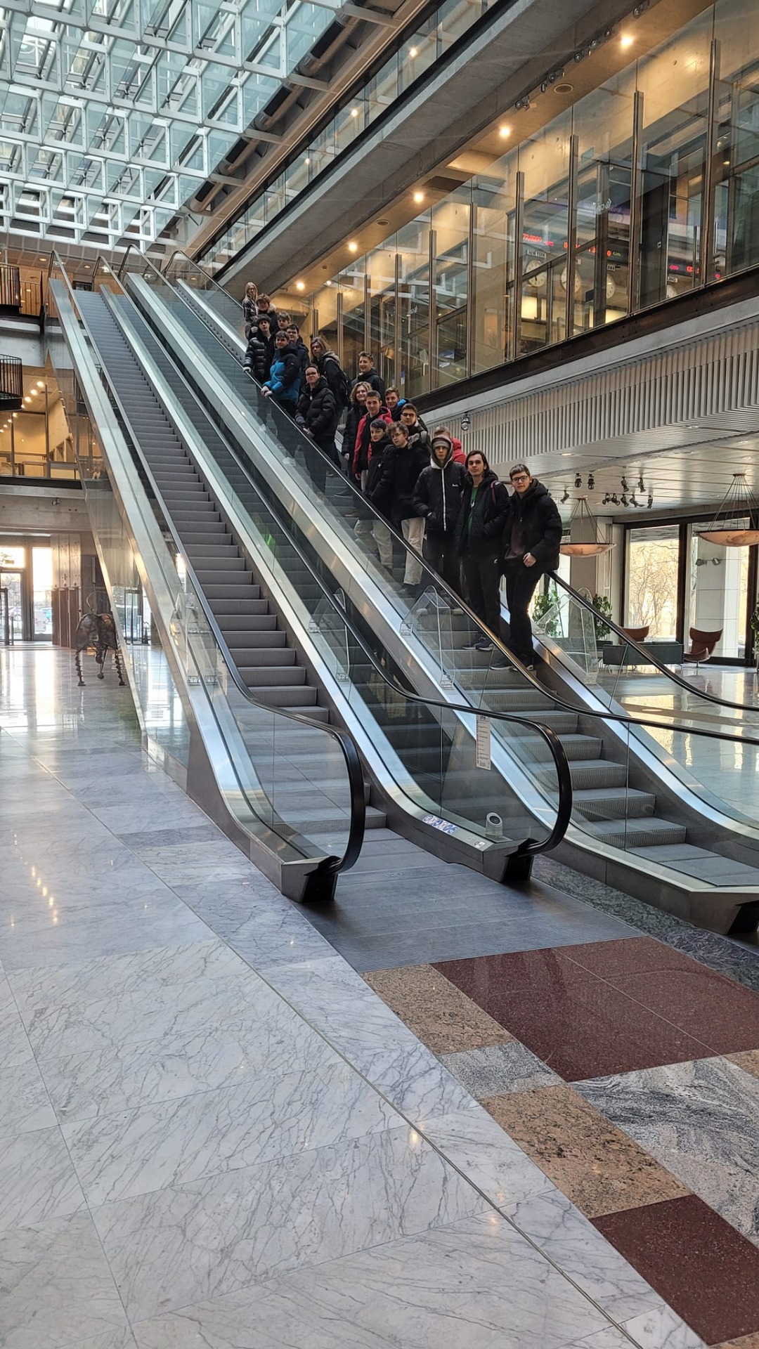 Uczniowie na ruchomych schodach w budynku GPW. 