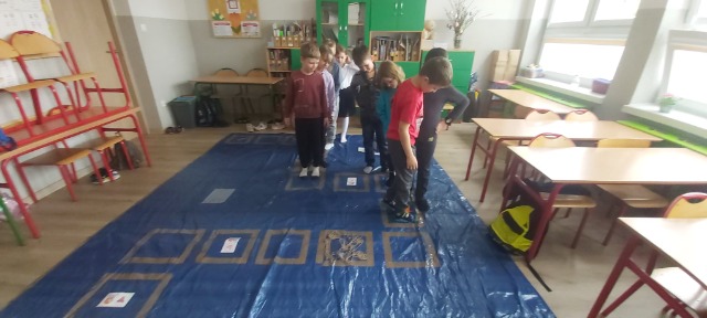 Grupa dzieci gra na podłodze w wielkoformatową grę.