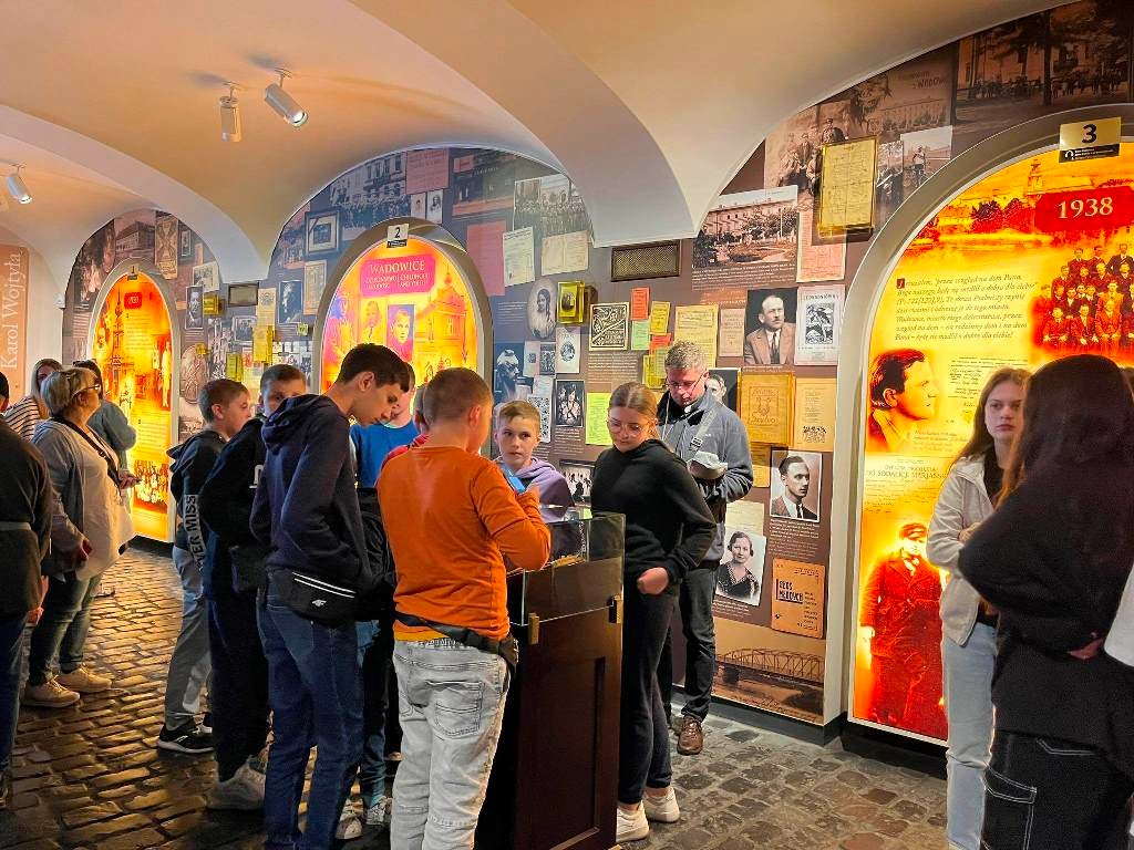 Zdjęcie przedstawia uczniów, którzy oglądają eksponaty w Muzeum Ojca Świętego Jana Pawła II.