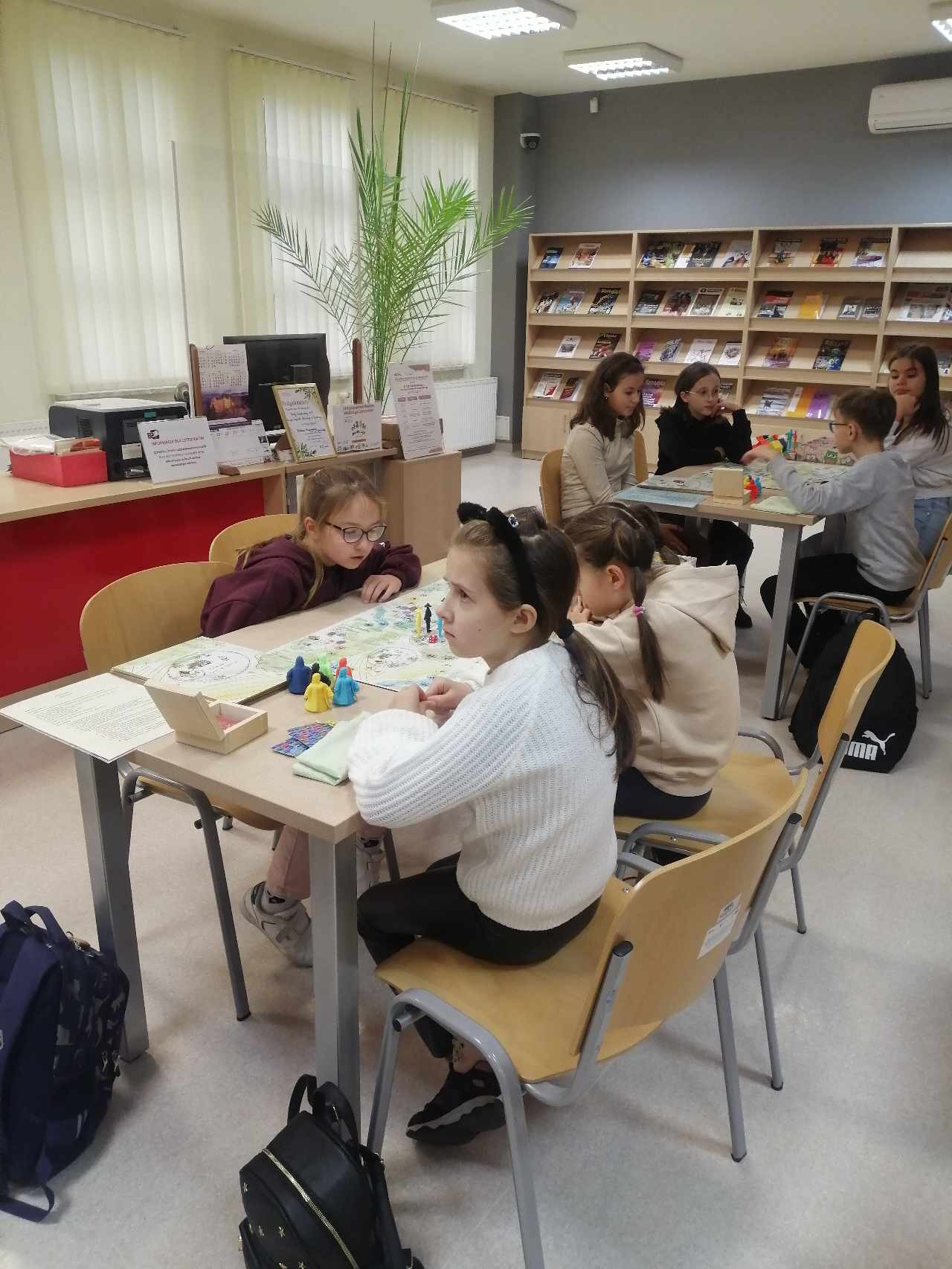 Uczniowie klasy III i V  w Bibliotece Pedagogicznej w Tarnobrzegu  grają w grę planszową "Lasowiak - zostań najbogatszym mieszkańcem wsi".