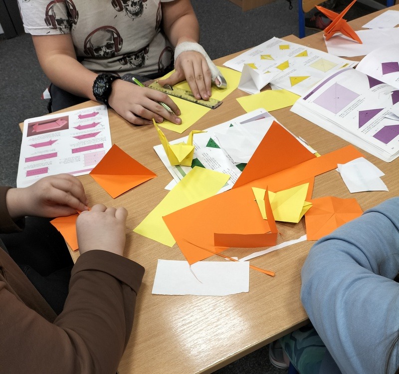 uczniowie składają żurawie z kolorowego papieru