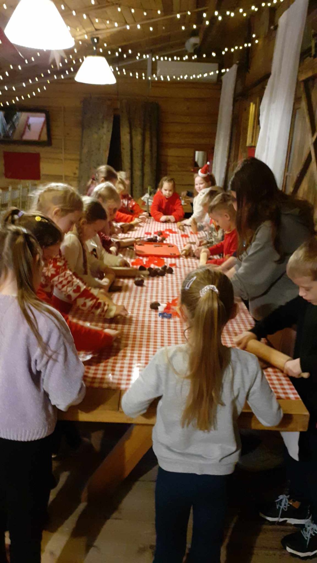 Uczniowie przy długim stole uczą się robienia pierników.