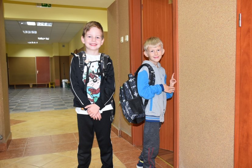 Dwóch uczniów z plecakami na  szkolnym korytarzu